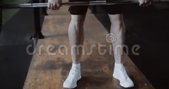 特写年轻肌肉发达的白种人运动员在大型硬核健身房中用重物横杠锻炼慢动作视频的预览图
