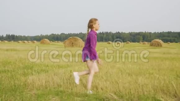 可爱的女孩奔跑乡村田野干草堆夏日风景视频的预览图