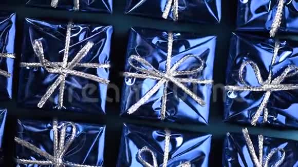 蓝色背景上的蓝色礼盒圣诞节和新年的旋转背景现在惊喜的概念视频的预览图