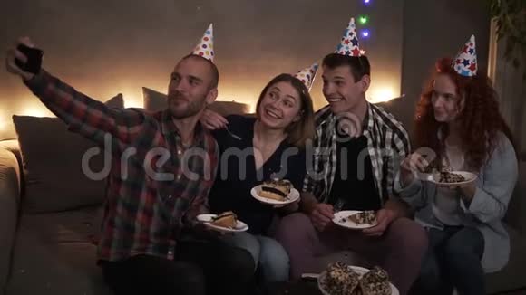 快乐的年轻的朋友或两对夫妇在庆祝生日的时候他们一起坐在节日的圆锥体上视频的预览图