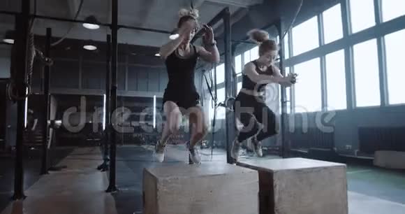 两个年轻的快乐美丽的运动白人妇女一起运动在大型健身房跳大块慢动作视频的预览图
