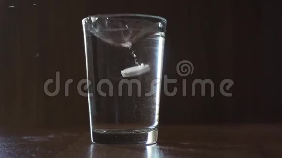 药物在棕色背景下落入一杯水中视频的预览图