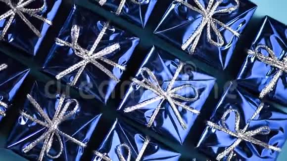 蓝色背景上的蓝色礼盒圣诞节和新年的旋转背景现在惊喜的概念视频的预览图