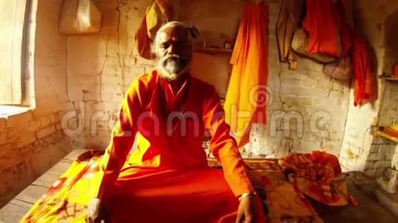 古色古香的印度僧人穿着橙色衣服脖子上挂着祈祷珠房间里挂着瓦工和墙上的衣服视频的预览图