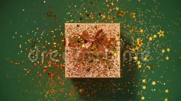 女人手打开礼盒闪耀着金色的星星闪闪发光的纸屑绿色背景下的免费礼品视频的预览图