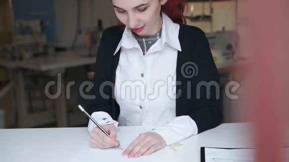 女时装设计师在灯光车间绘制一件连衣裙的草图视频的预览图