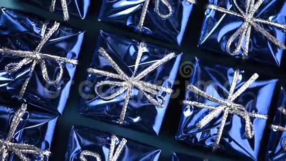 蓝色背景上移动蓝色礼品盒圣诞节和新年的旋转背景现在惊喜的概念视频的预览图