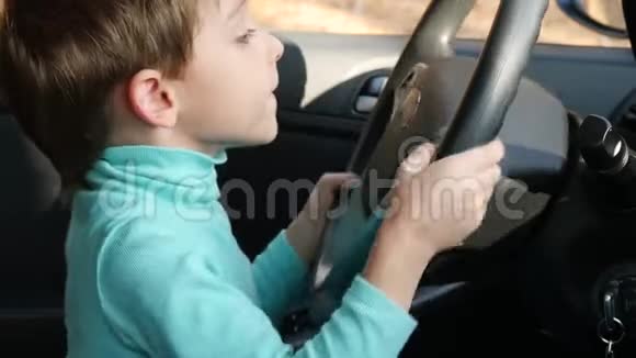 一个小男孩转动坐在汽车座位上的汽车的轮子视频的预览图