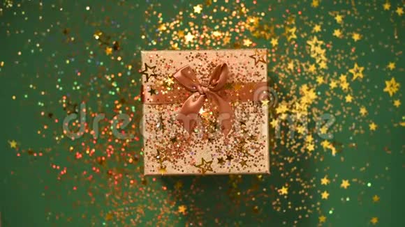 闪闪发光的金色星星绿色背景上的礼品盒上闪闪发光的纸屑上景圣诞节和新年的质地视频的预览图