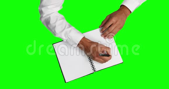一个高加索人在绿色屏幕的笔记本上画图的俯视图视频的预览图