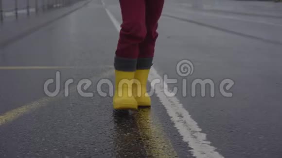 穿黄色橡胶靴的孩子沿着灰色沥青路走视频的预览图