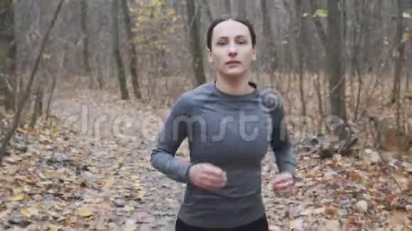 可爱专注的女人在秋季公园慢跑然后进行半程马拉松比赛运行概念视频的预览图