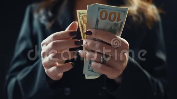 特写年轻的女商人正在数钱在黑色背景上4k视频的预览图