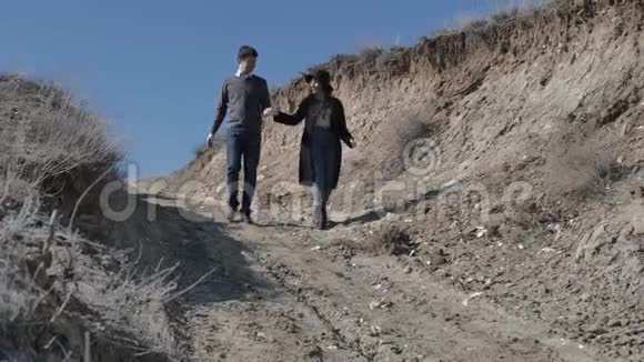 年轻的一对夫妇双手相拥沙丘下阳光明媚的春天视频的预览图