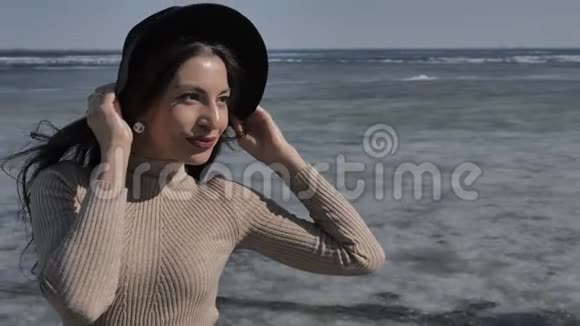 戴着黑帽子的漂亮女孩正在镜头前看着背景河里覆盖着冰视频的预览图