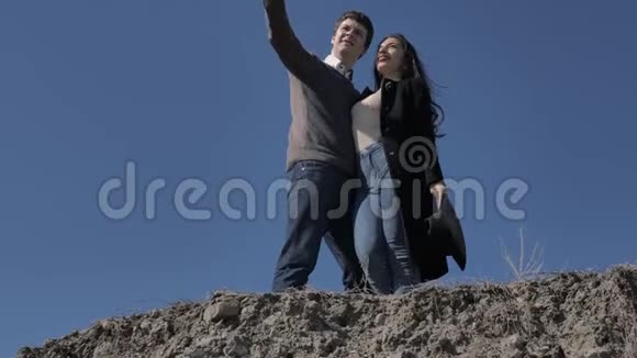 年轻夫妇站在山上背景是蓝天阳光明媚的春天视频的预览图