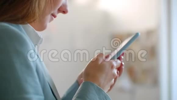 特写一位年轻的女设计师在裁缝工作室里在缝纫车间里用手机写字视频的预览图