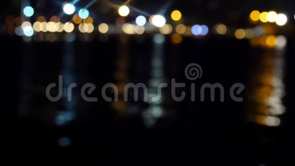 色彩斑斓的离焦海滨城市的夜灯闪烁和挥动的倒影视频的预览图