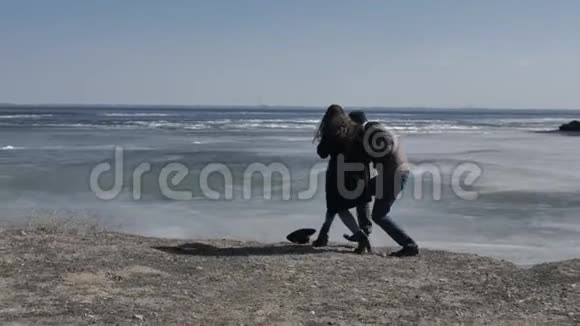 这对年轻夫妇沿着河岸走着浑身是冰阳光明媚的春天视频的预览图