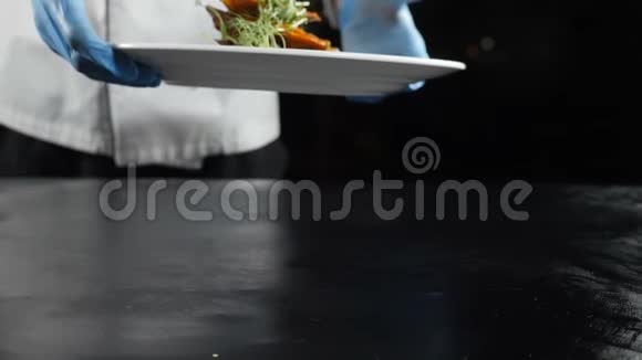 慢动作食物视频概念厨师双手戴手套在豪华餐厅里放白色盘子和美味的海鲜菜视频的预览图