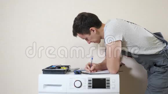 男士在剪贴板上写字检查现代洗衣机视频的预览图
