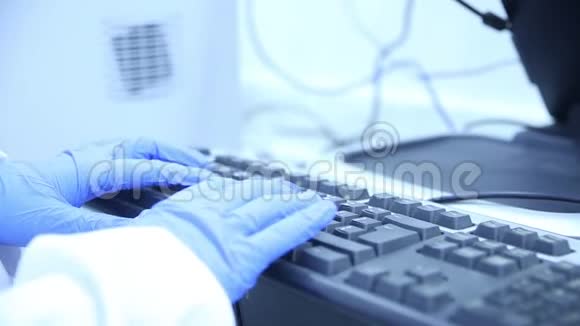 实验室技术人员穿着白色的实验室外套戴着蓝色的乳胶手套在键盘上打字视频的预览图
