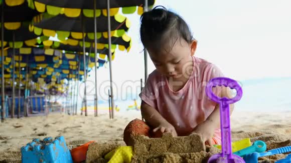 可爱的两岁亚洲女婴在海滩上玩海滩玩具暑假家庭假期视频的预览图
