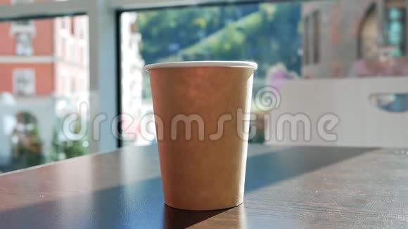 年轻女子从桌子上拿起咖啡馆里的纸杯茶喝茶把杯子放在桌子上窗外的倒影视频的预览图