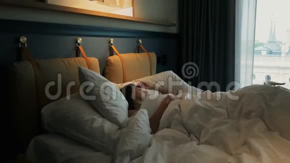 漂亮的年轻女子清晨睡在酒店房间里躺在床上视频的预览图
