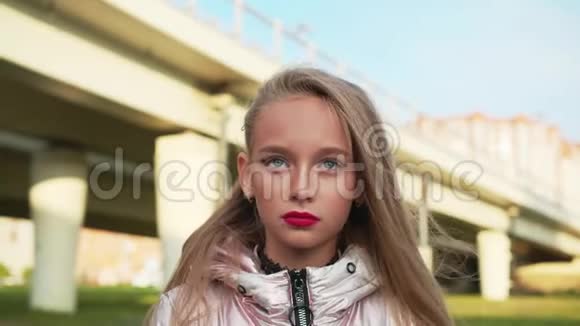 肖像少年女孩明亮的妆容嘴唇和眼睛在车桥背景长脸金发少女视频的预览图