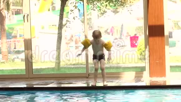 一个手上拿着充气袖子的小男孩跳进水池里视频的预览图