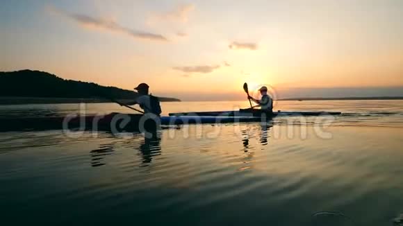 日落时分人们正驾驶独木舟穿过湖面视频的预览图