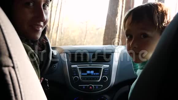 一家人坐汽车旅行一个女人和一个孩子坐在车里回头看微笑视频的预览图