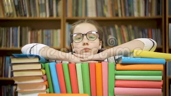 女孩读完一本书后摘下眼镜一个女孩躺在图书馆的书上视频的预览图