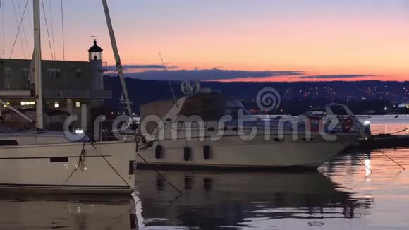 日落过海港游艇灯塔和朝城市灯光方向的景观视频的预览图