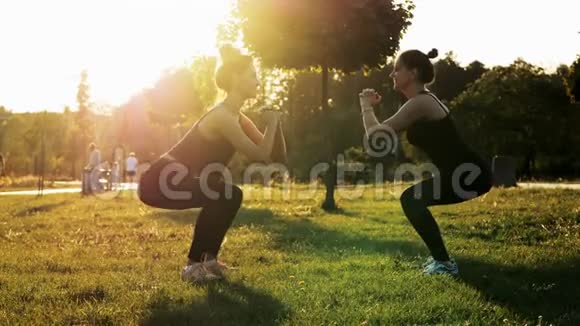 日落时分两名运动女子一起在公园里训练和蹲坐健身有氧运动和伸展运动健康视频的预览图