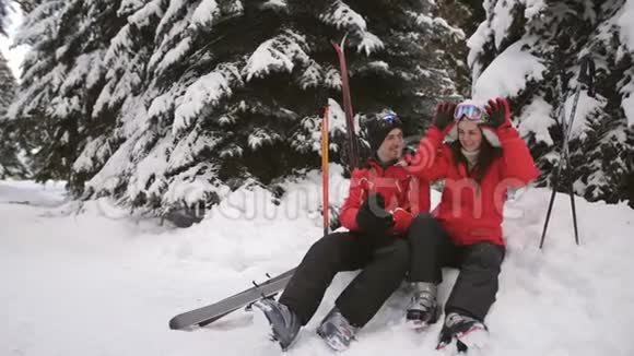 幸福的滑雪者一家人坐在一起穿着滑雪服躺在雪地上视频的预览图