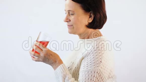 女人喝白色背景的红汁视频的预览图