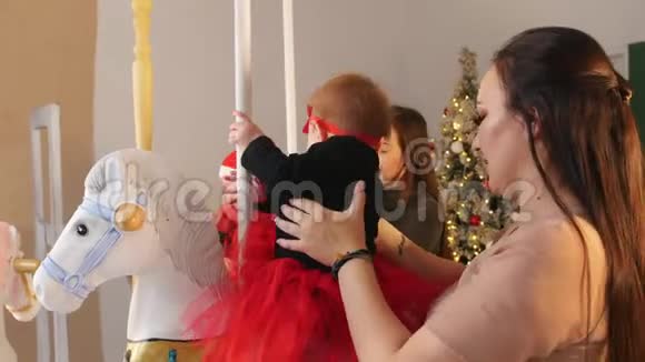 圣诞节概念两个婴儿和他们的母亲坐在旋转木马马上视频的预览图