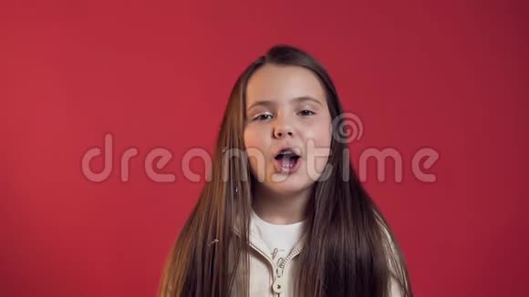 可爱活泼的小女孩带着牙套在红色背景上对着镜头吹金色的纸屑视频的预览图