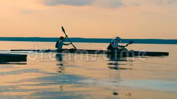 划艇者在皮划艇上穿过日落湖的侧景视频的预览图