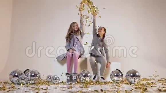 两个年轻女孩在迪斯科球附近慢镜头在头上抛着金色的纸屑视频的预览图