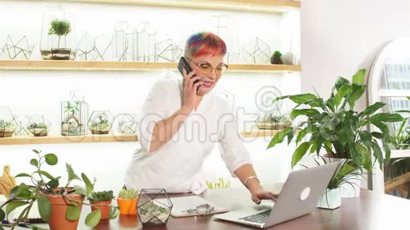 高级女性花店老板站在植物周围打电话交谈视频的预览图