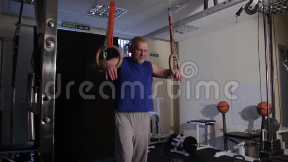强壮的运动员在俯卧撑年龄和L坐在体操环上视频的预览图