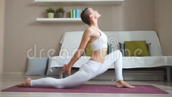美丽的女孩在家做运动练习瑜伽作为健康和美容锻炼的身体视频的预览图