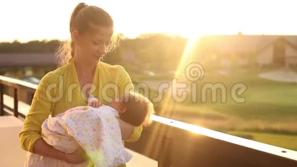 一组视频穿着黄色上衣的女人用粉红色毯子把她的小婴儿轻轻地抚摸起来视频的预览图