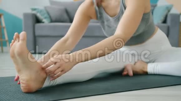 在家做瑜伽的漂亮女孩的特写以坐姿屈膝于垫子上视频的预览图