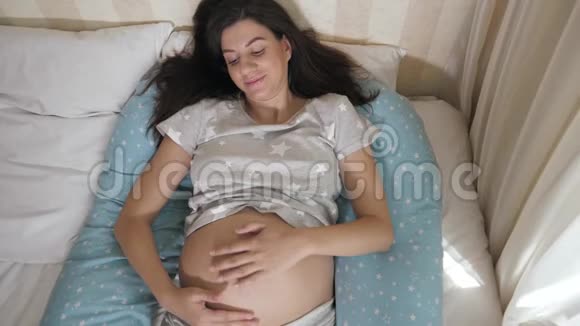 孕妇用手在床上抚摸腹部视频的预览图