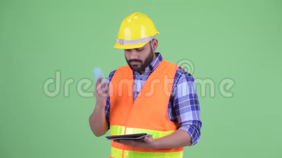 快乐超重留着胡须的印度工人在使用手机和数码平板电脑时工作视频的预览图