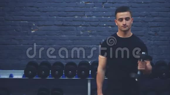 运动的年轻人穿着黑色T恤一个有运动身体的人摇动哑铃的肌肉在这段时间里视频的预览图